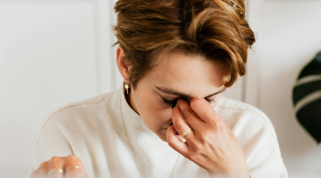 woman in pain, holding her nose due to her headache
